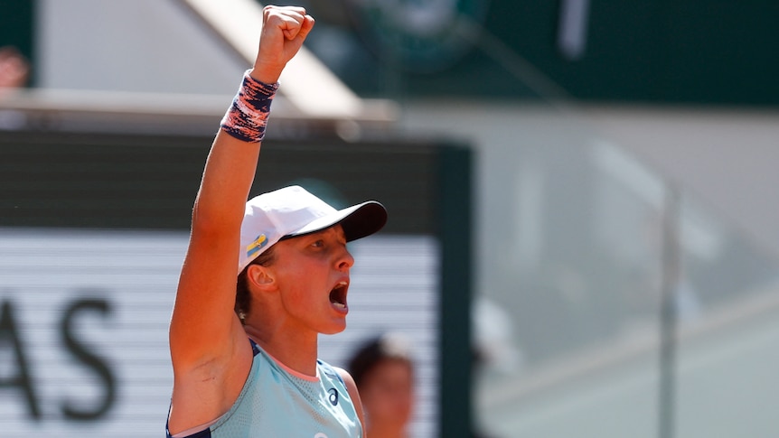 A tennis player raises her fist in the air in triumph.