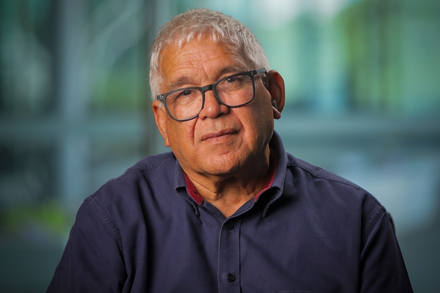 Indigenous man wearing a navy shirt and glasses.