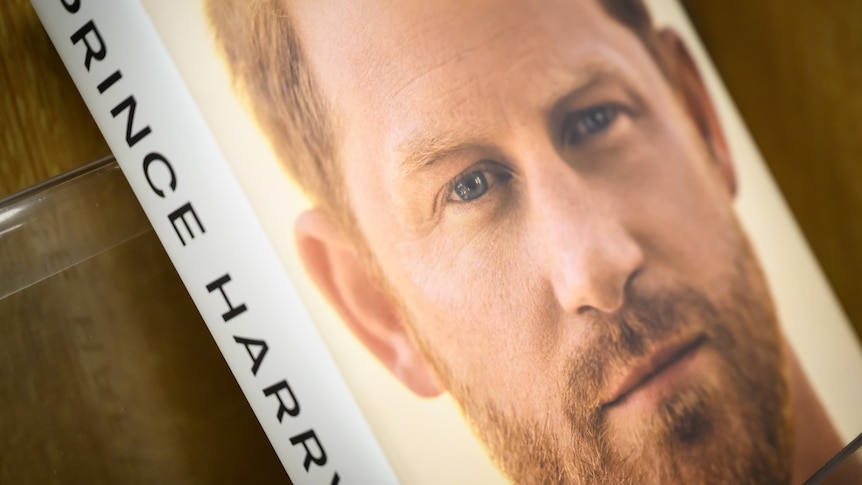 A copy of Prince Harry's memoir, showing his name on the spine and his unsmiling bearded face