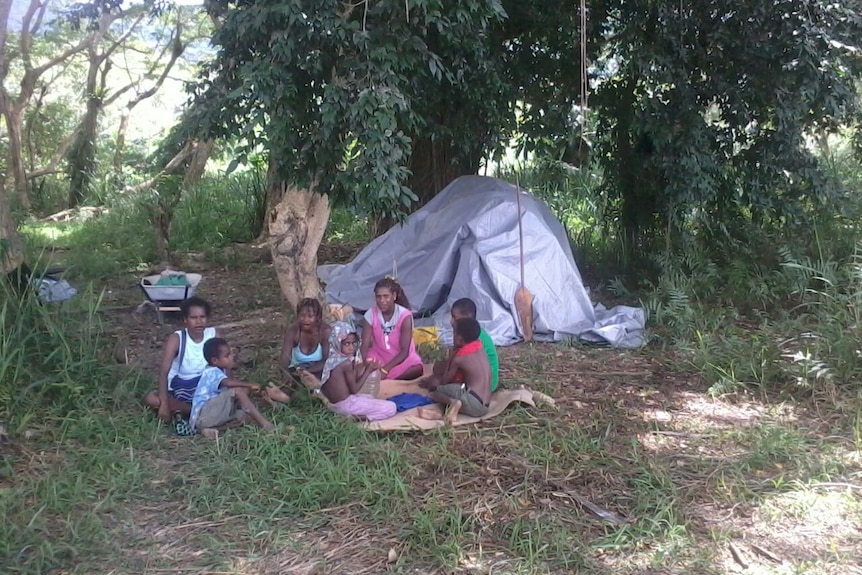 Locals sit after a sinkhole destroys homes