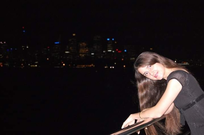 Woman leaning on railing facing a camera.