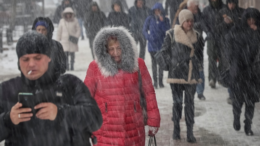 People walk during snowfall.