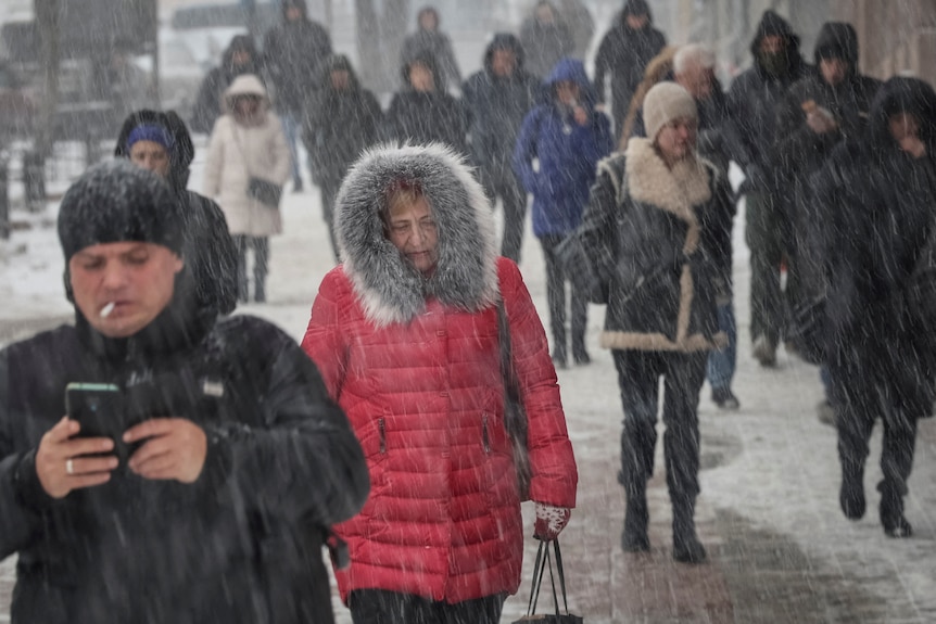 People walk during snowfall.