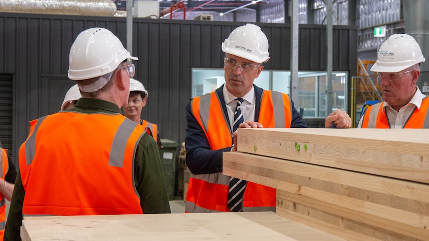 peter malinauskas stands in front of cross laminated timber speaking with worker