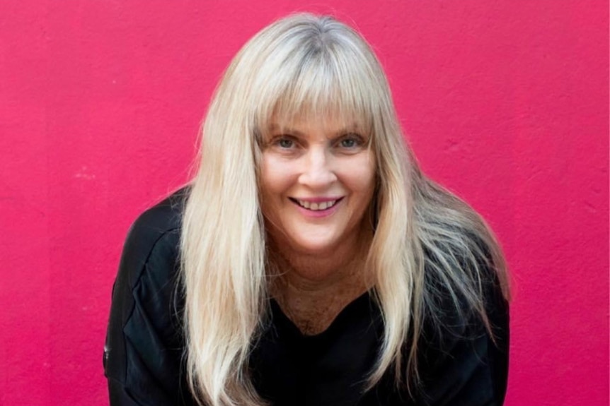 A portrait of a woman resting on her arms and smiling at the camera.