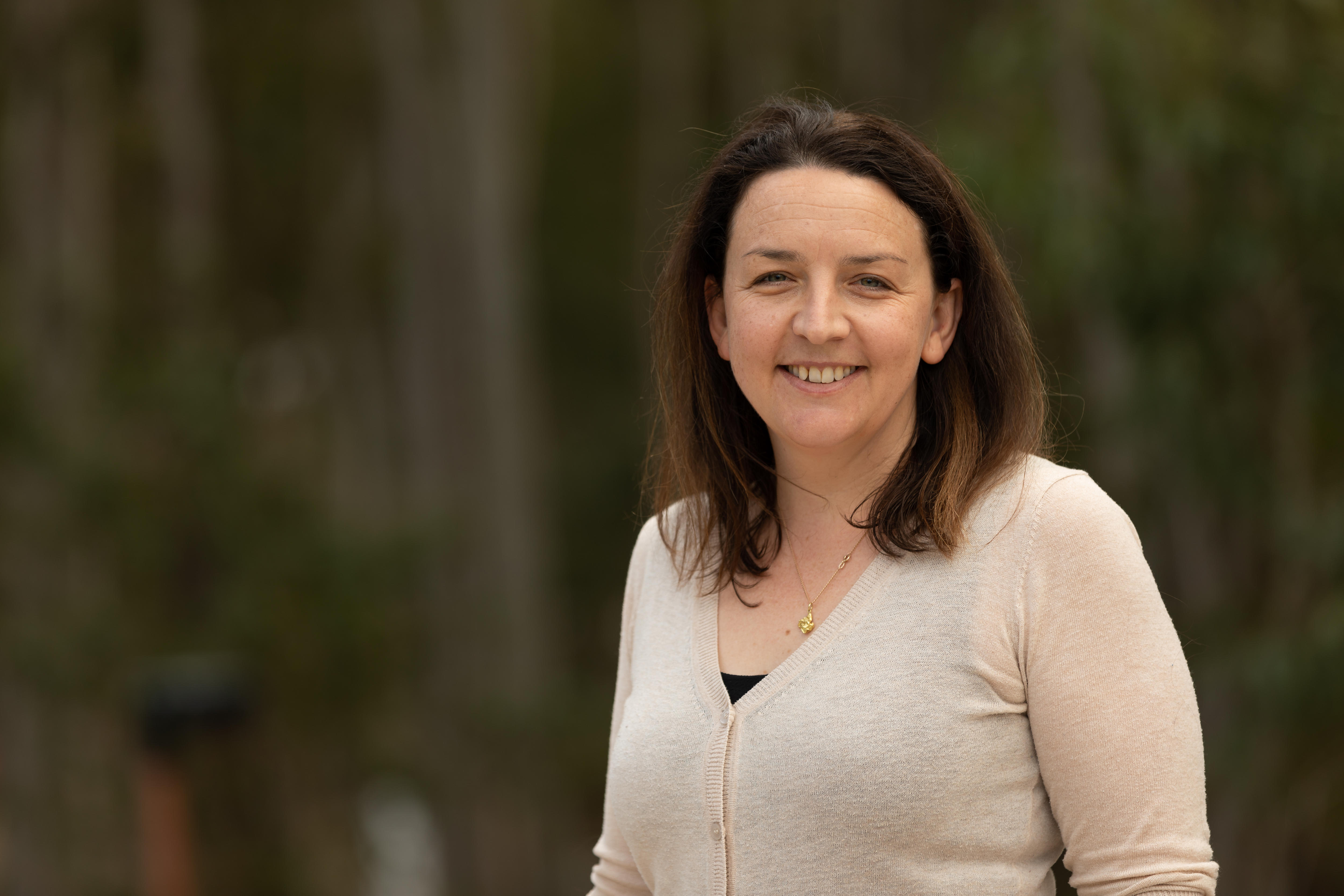 A woman with brown hair smiles at camera.