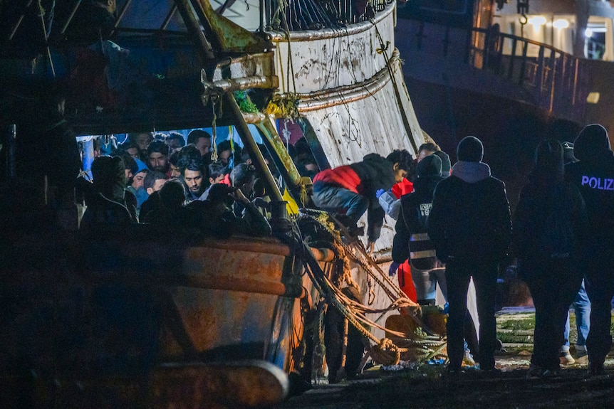 Refugees disembark a boat after rescue in Italy.