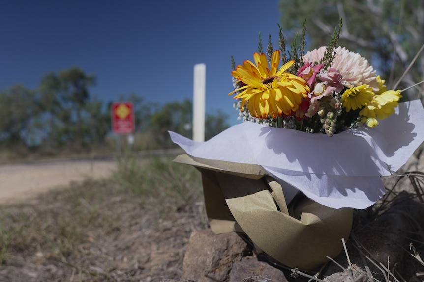 A bunch of flowers sits beside a country road.