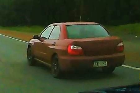 A red subarbu is spotted driving along the sunshine coast highway.