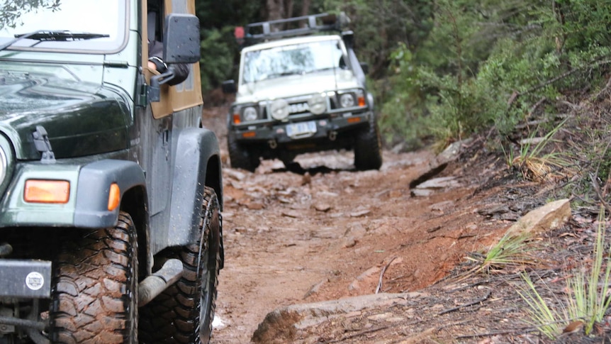 Four wheel driving enthusiasts driving down a muddy track in southern Tasmania