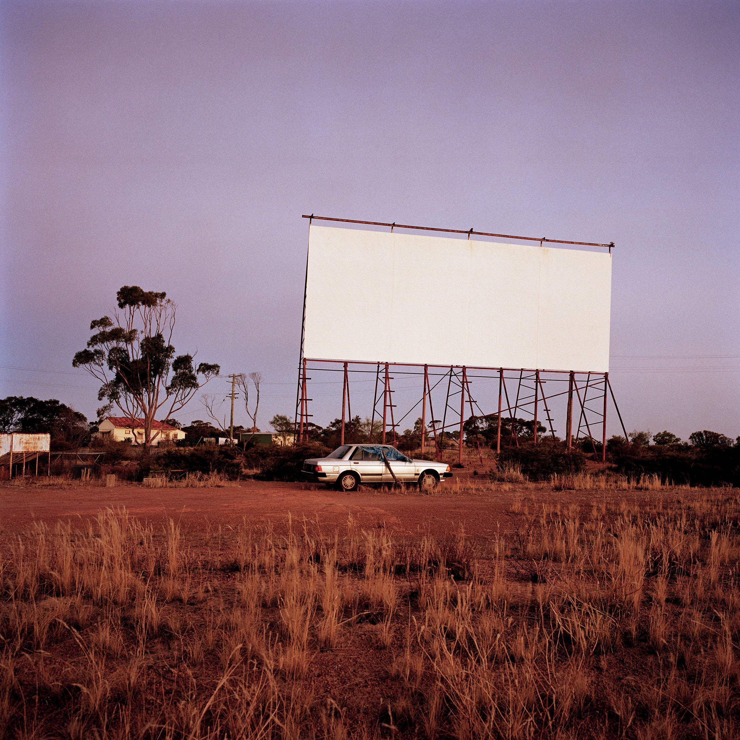 A blank white drive-in screen in front of a dark purple sky