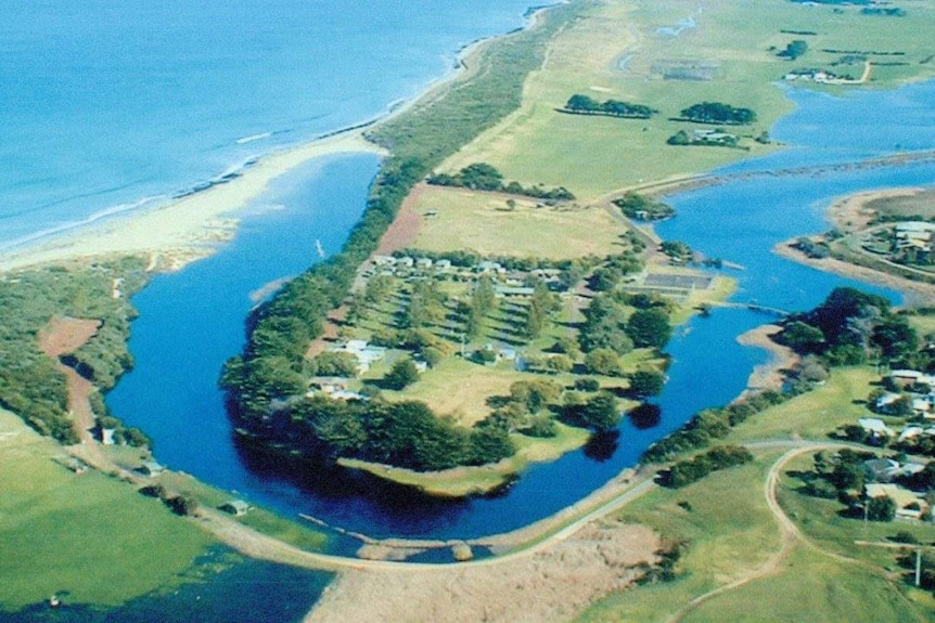 Aerial view of a river, with a small ridge of sand between the river and the ocean.