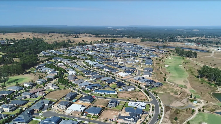 Aerial photo of a block of new-looking houses and a road with farmland around the development.