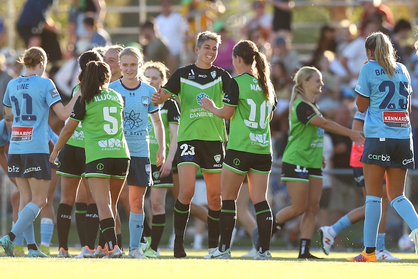 Canberra United players smile with each other while shaking hands with Sydney FC players