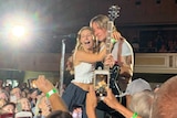 Country singer Keith Urban gives his guitar to a teenage girl on stage
