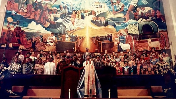 Picture of a choir standing infront of a big mural 