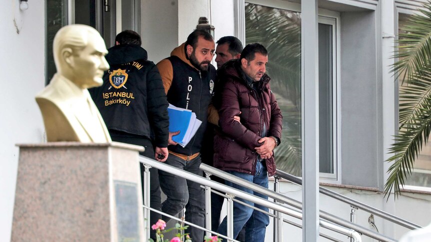 Turkish police officers escort a man in handcuffs