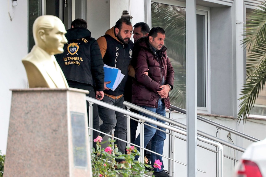 Turkish police officers escort a man in handcuffs