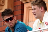 Australia Test players Mitch Marsh, in training gear and sunnies, and Cameron Green, in whites, talk on a balcony.