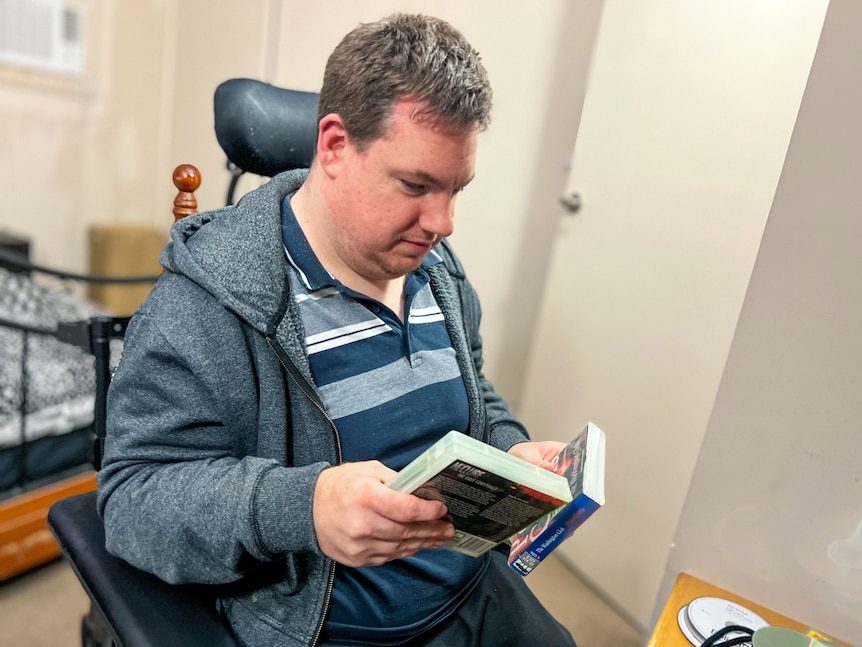A man in a wheelchair holding some books