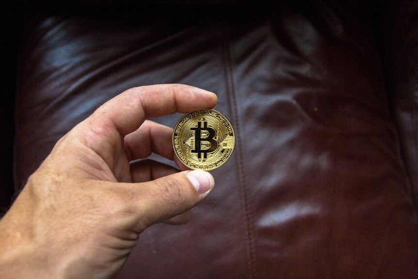 A person holding a Bitcoin in their hand.