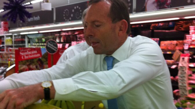 Tony Abbott reaches across bananas