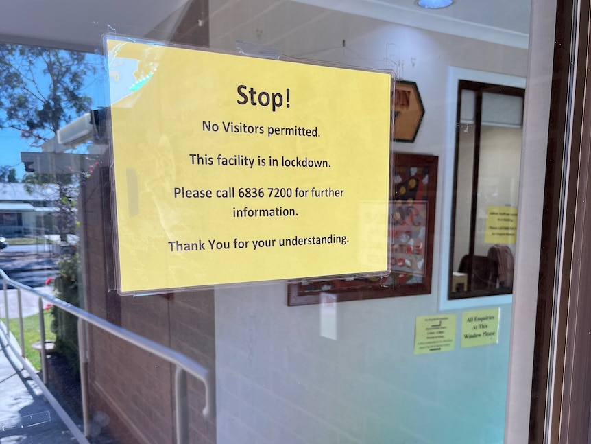 Yellow sign on glass door says no visitors permitted to enter