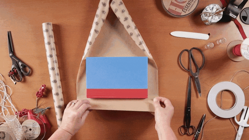GIF of wrapping paper folding over a book to depict how to wrap gifts like a pro.