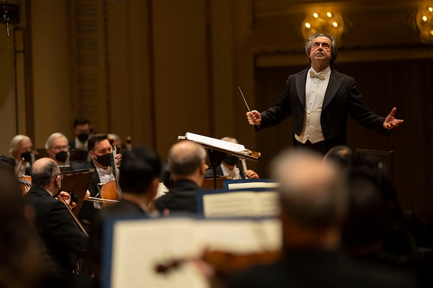Riccardo Muti leads the Chicago Symphony Orchestra, viewed from behind the violin section.