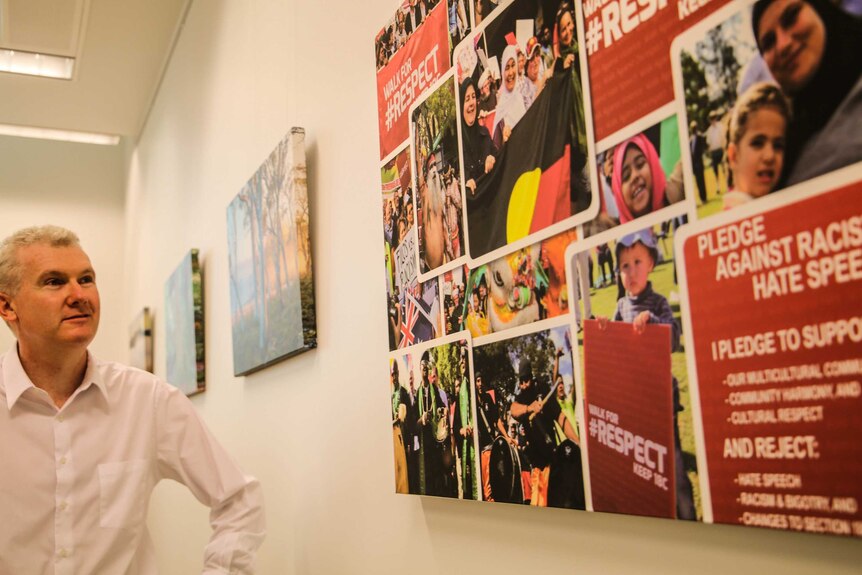 Tony Burke admires photos on his office wall from a walk against racist hate speech.