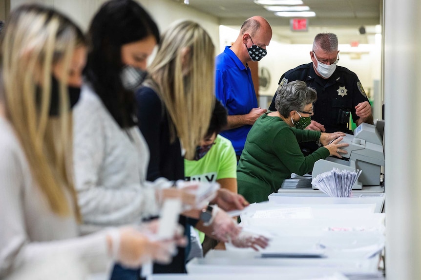 Election workers prepare ballots for counting.
