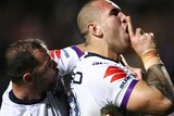 Nelson Asofa-Solomona holds his index finger up to his mouth in a "shh" motion while Cameron Smith hugs him from behind.