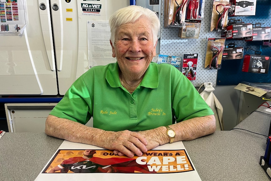 woman in green shirt smiles behind a shop counter