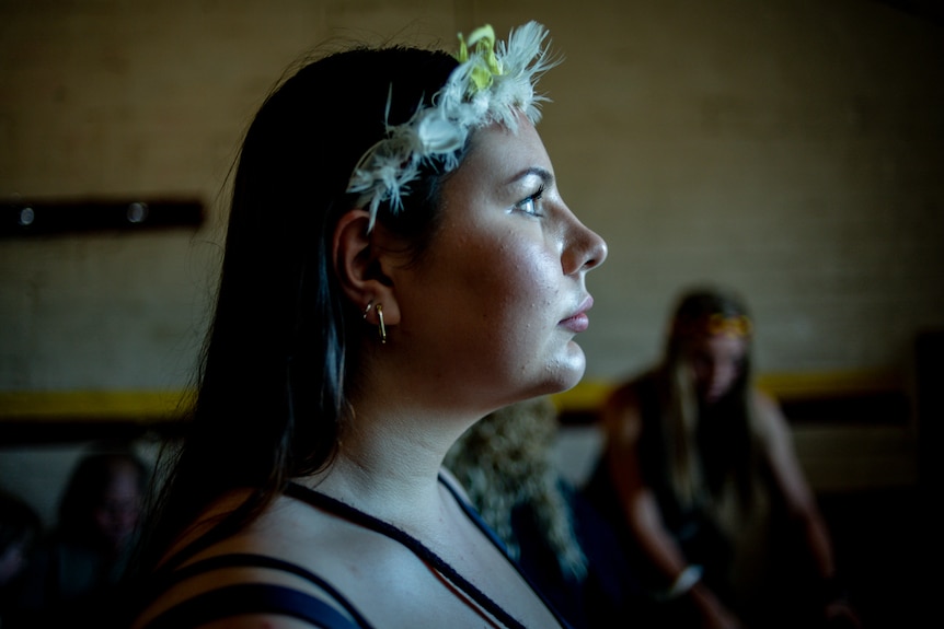 Girl wearing a feathered Indigenous headband looks up towards the light.