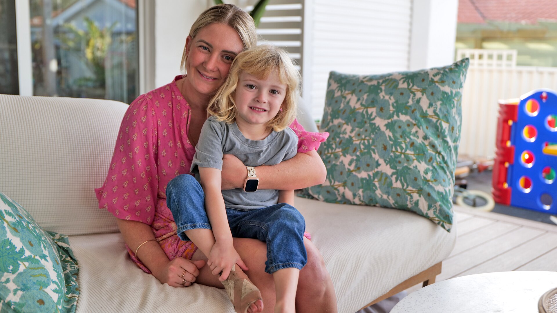 Small child holds bandaged foot and sits on mother's lap