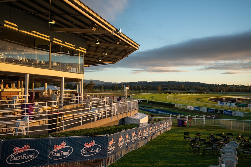 A racing club's stands and corporate box at sunrise. Track is in the background and empty chairs are in foreground