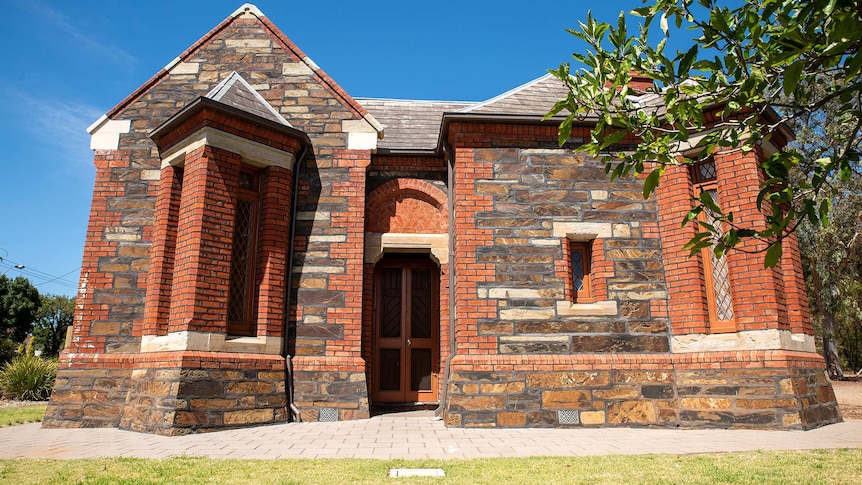 A bluestone and brick building stands sharp against blue skies.