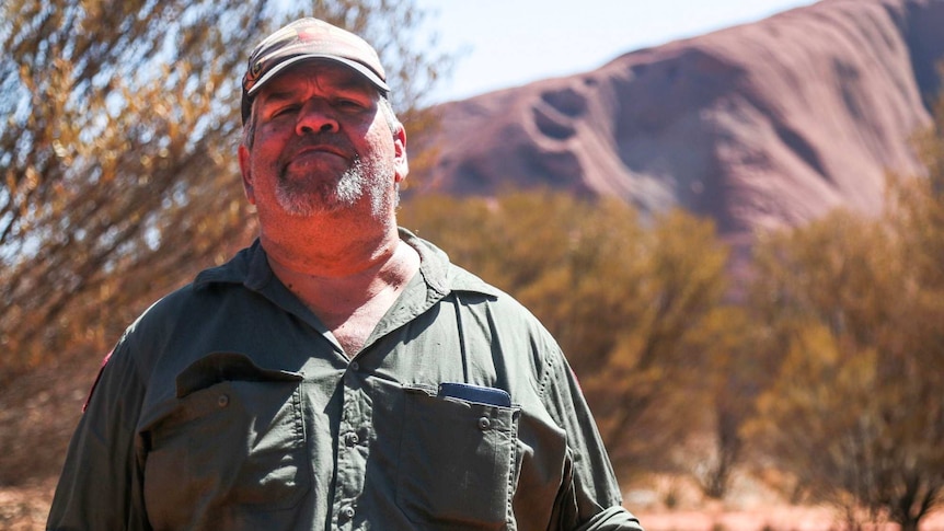 Leroy Lester stands in front of Uluru.