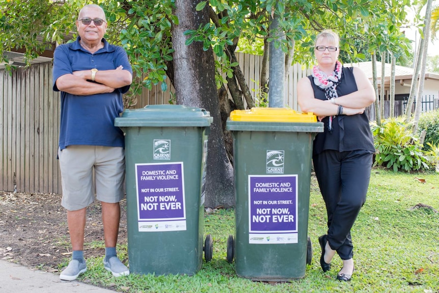 Cairns residents stand next to their wheelie bins with stickers displaying the message "Not in our Sreet. Not now, not ever."