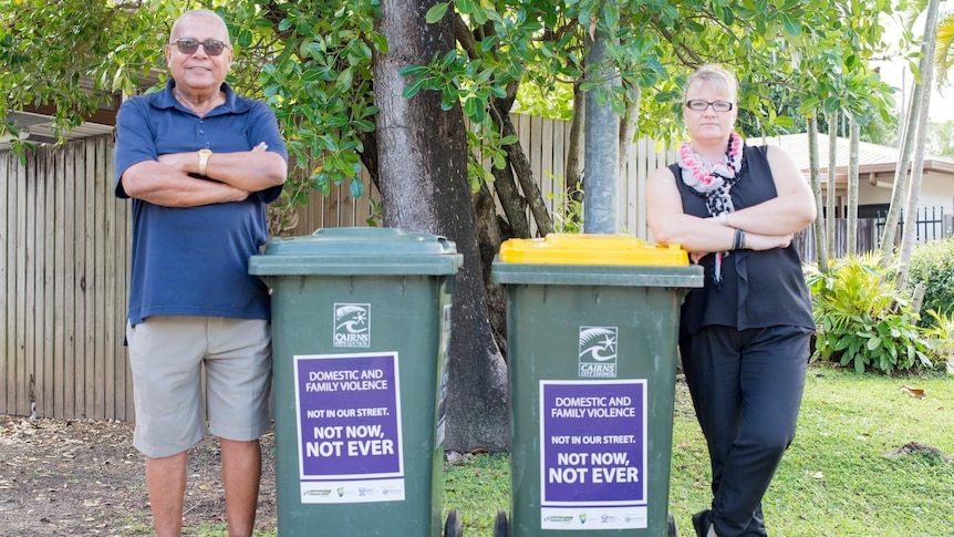 Cairns residents stand next to their wheelie bins with stickers displaying the message "Not in our Sreet. Not now, not ever."