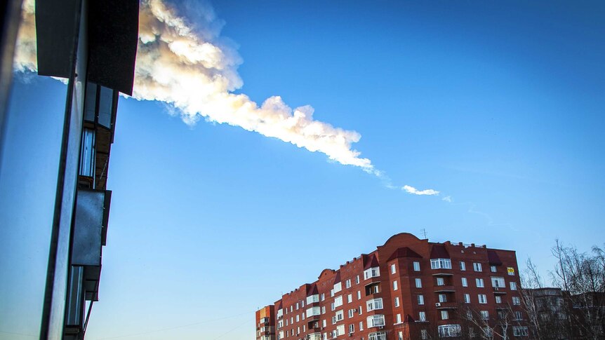 The trail of a falling object is seen above a residential apartment block in the Urals city of Chelyabinsk.