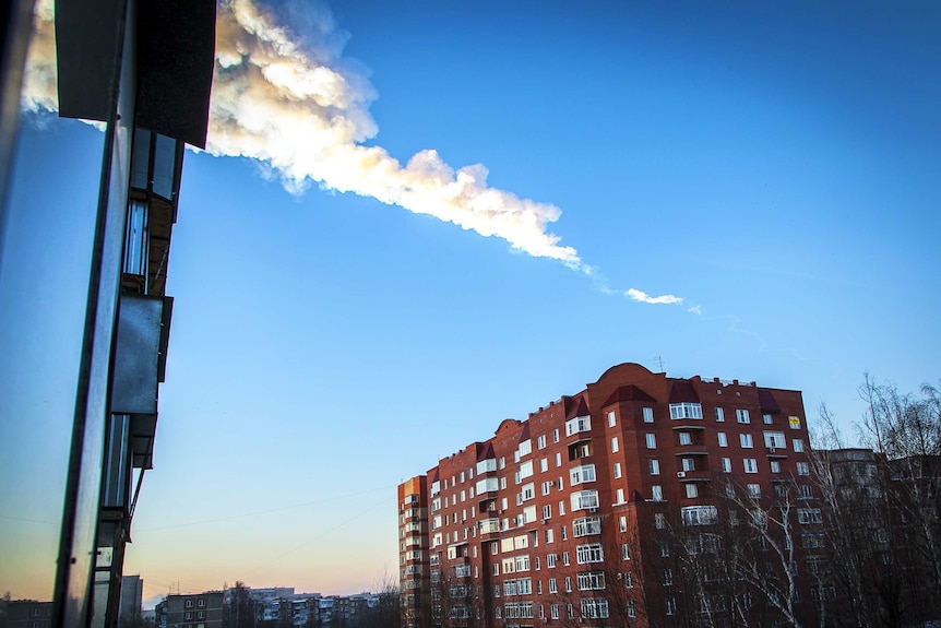 The trail of a falling object is seen above a residential apartment block in the Urals city of Chelyabinsk.