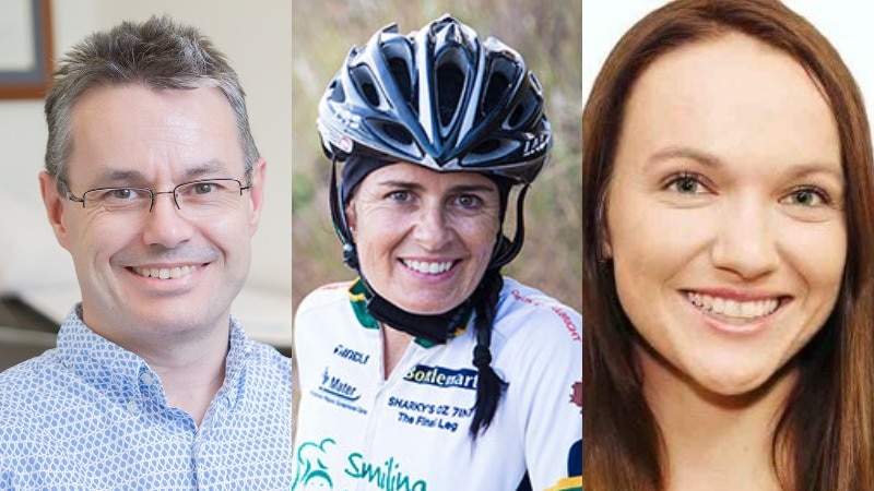 A smiling man with grey hair and glasses, a smiling woman wearing a helmet and cycling outfit and a smiling brunette woman.