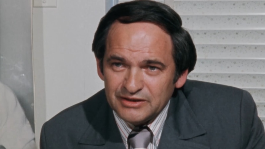 Close up of man with dark hair sitting at desk