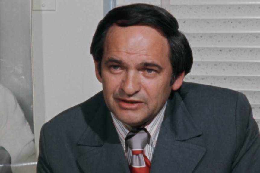 Close up of man with dark hair sitting at desk