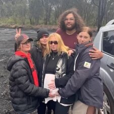 A pregnant Chrissy stands with her four children, some of their hands feel her belly.