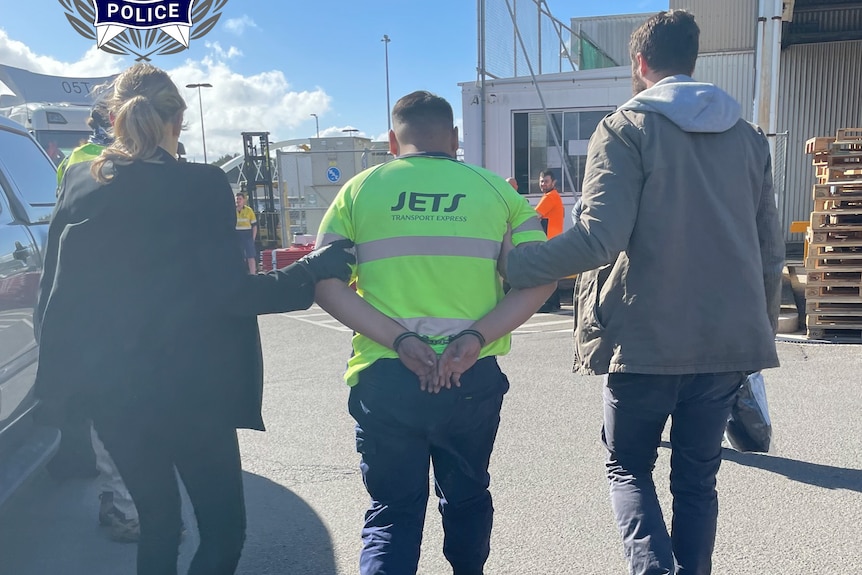 two AFP officers lead a man in handcuffs