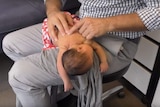 Melbourne chiropractor Ian Rossborough cracks a baby's back