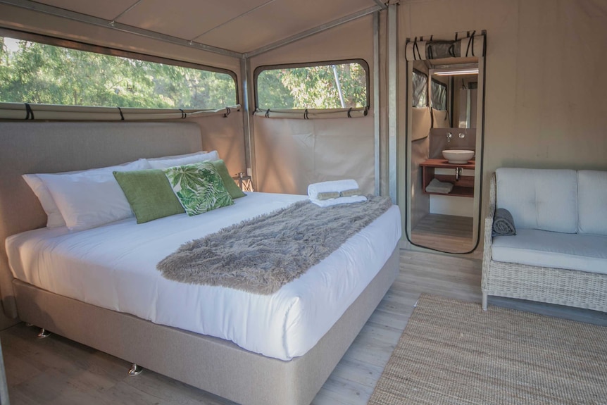 The inside of an eco tent showing a large bed, couch and bathroom.