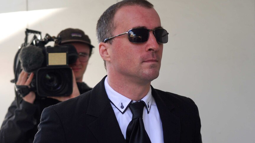 A mid shot of WA Police officer Andrew Barber outside a Perth court with a cameraman behind him.
